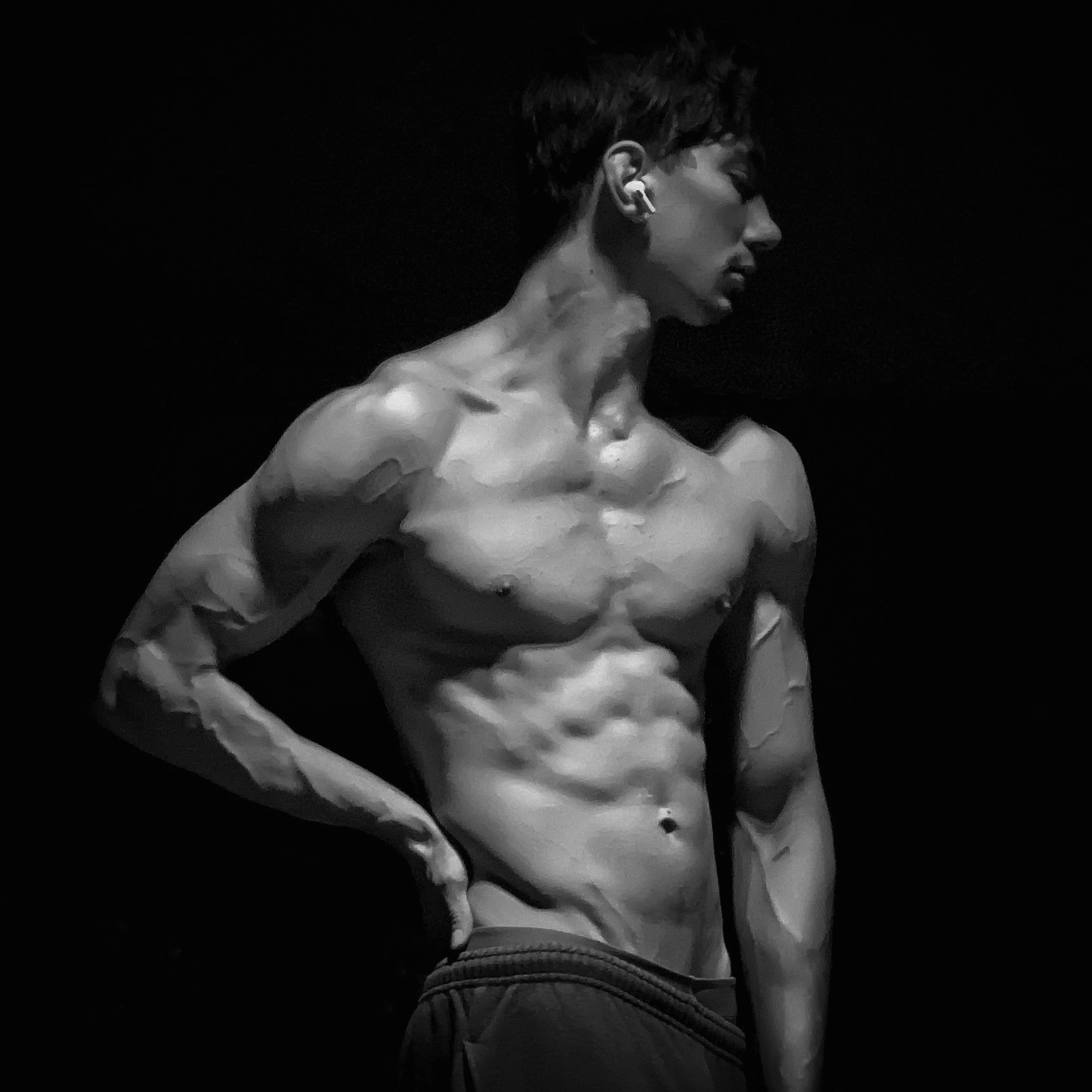 Andrew Valentine in profile, one arm raised, lit from the side against a dark ground.