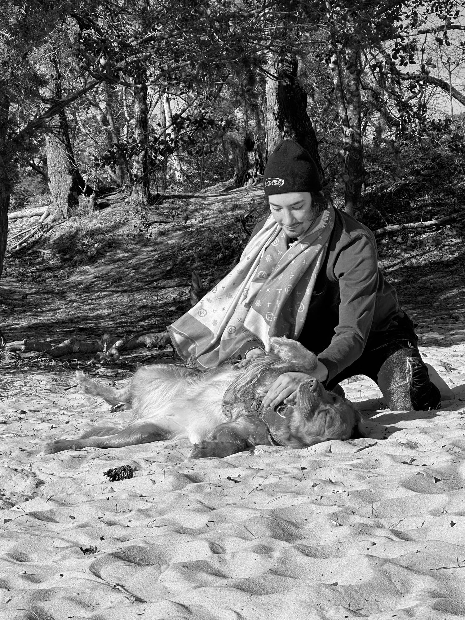 Andrew Valentine crouched on a beach with a dog, low winter light.