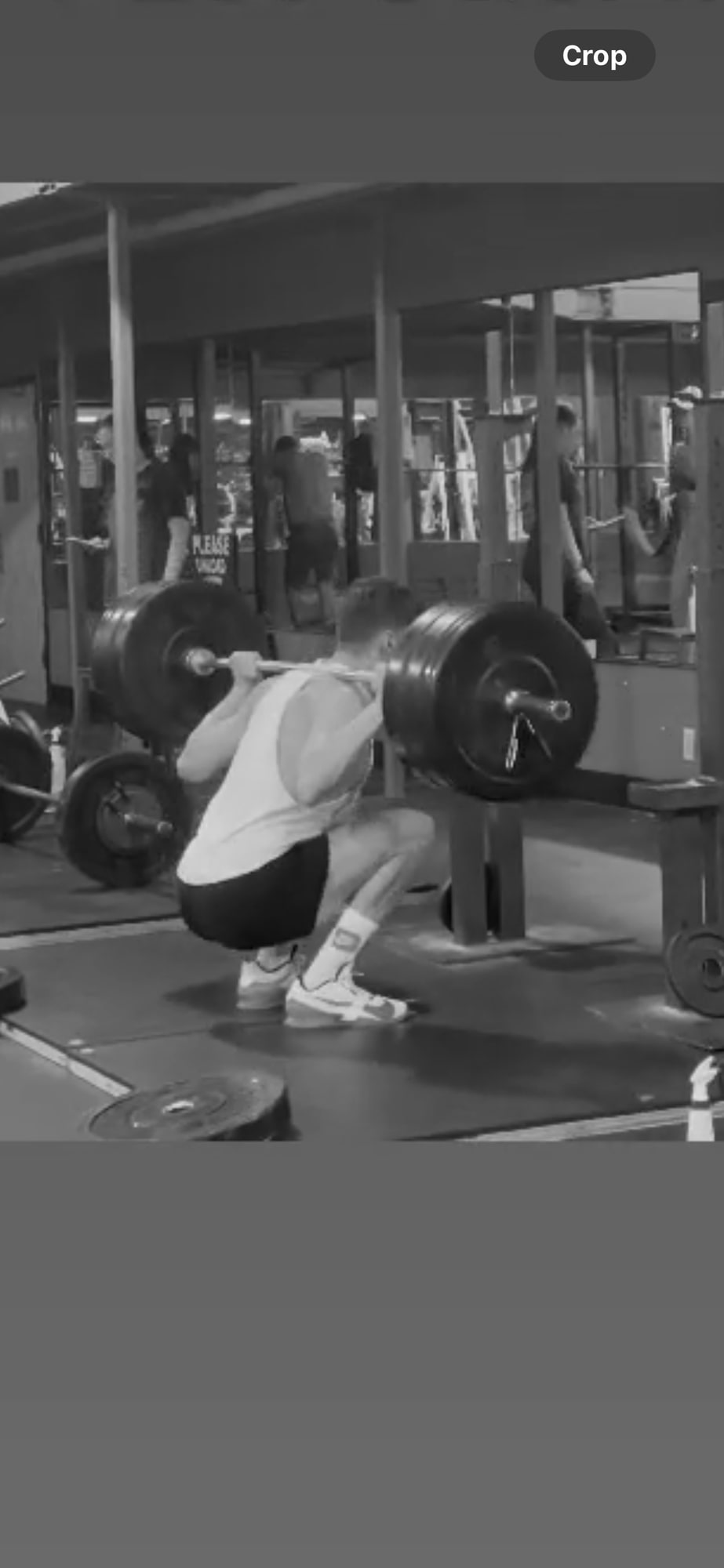 Andrew Valentine at the bottom of a loaded back squat in a commercial gym.