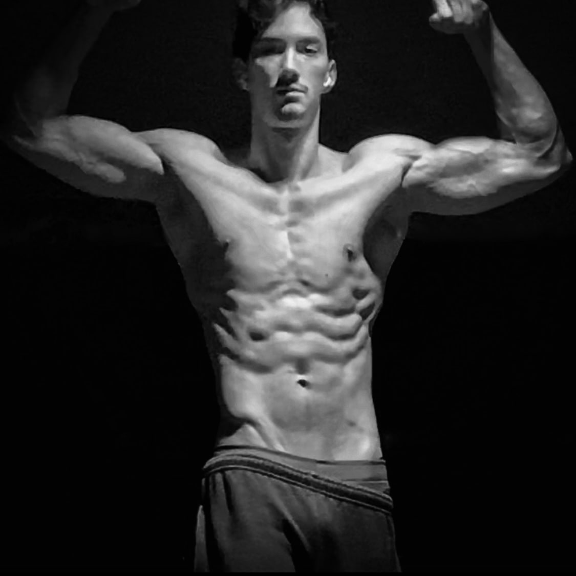 Approved press photograph of Andrew Valentine, front double biceps, dark ground.